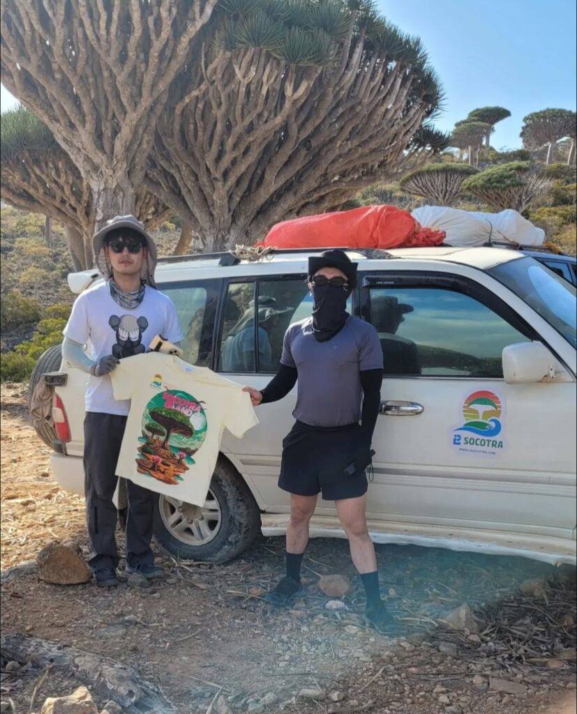 Tourist and guide beside a 2Socotra vehicle